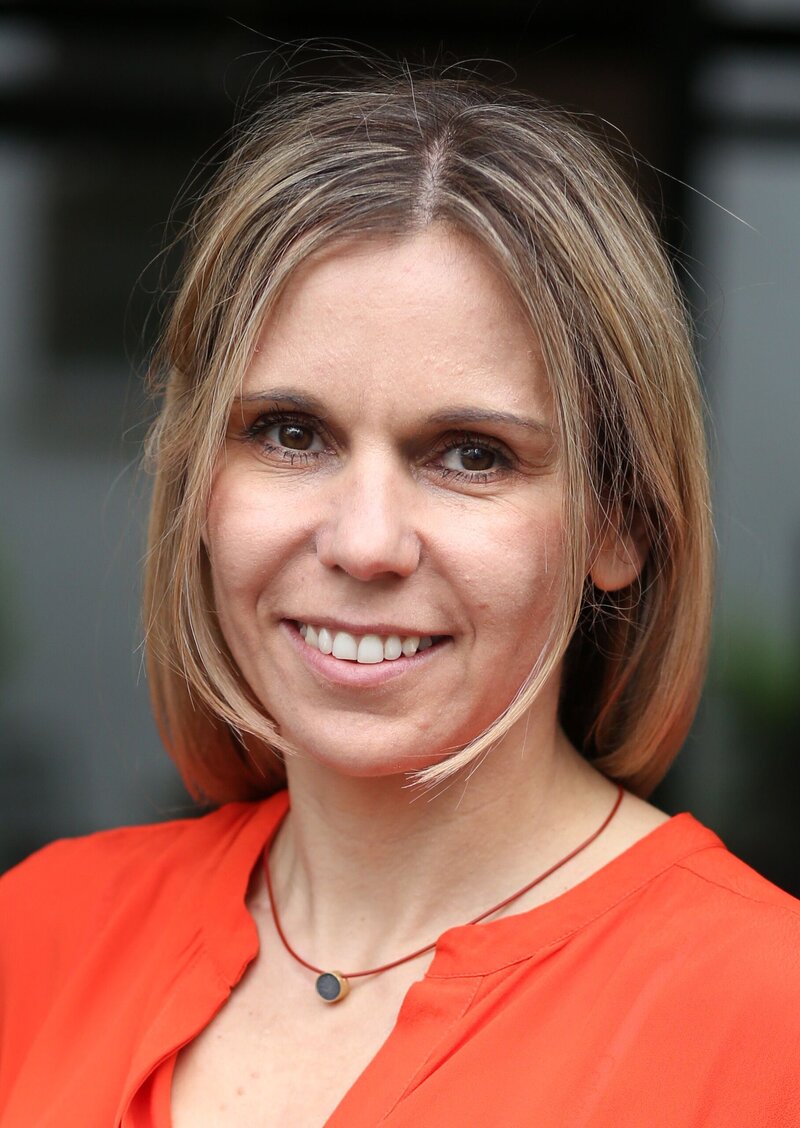 Woman in orange shirt smiling at camera