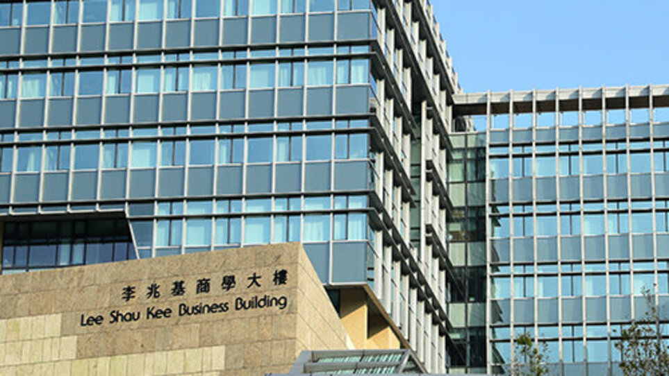 Ein modernes sechsstöckiges Glasgebäude mit Flachdach unter blauem Himmel auf dem Kellogg HKUST Campus