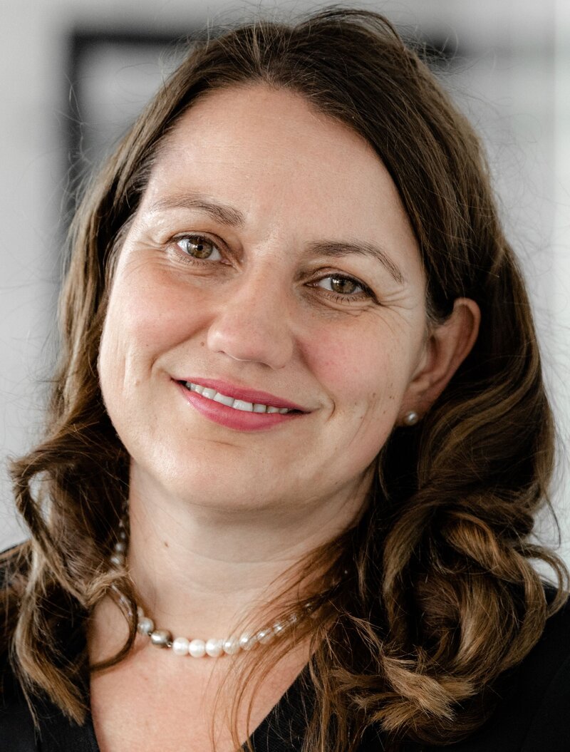 A woman with dark hair looks friendly into the camera