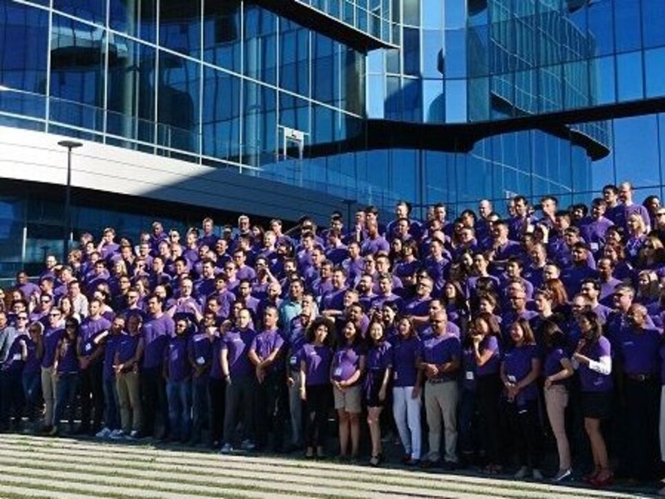 group of people in purple shirts standing in front of a building