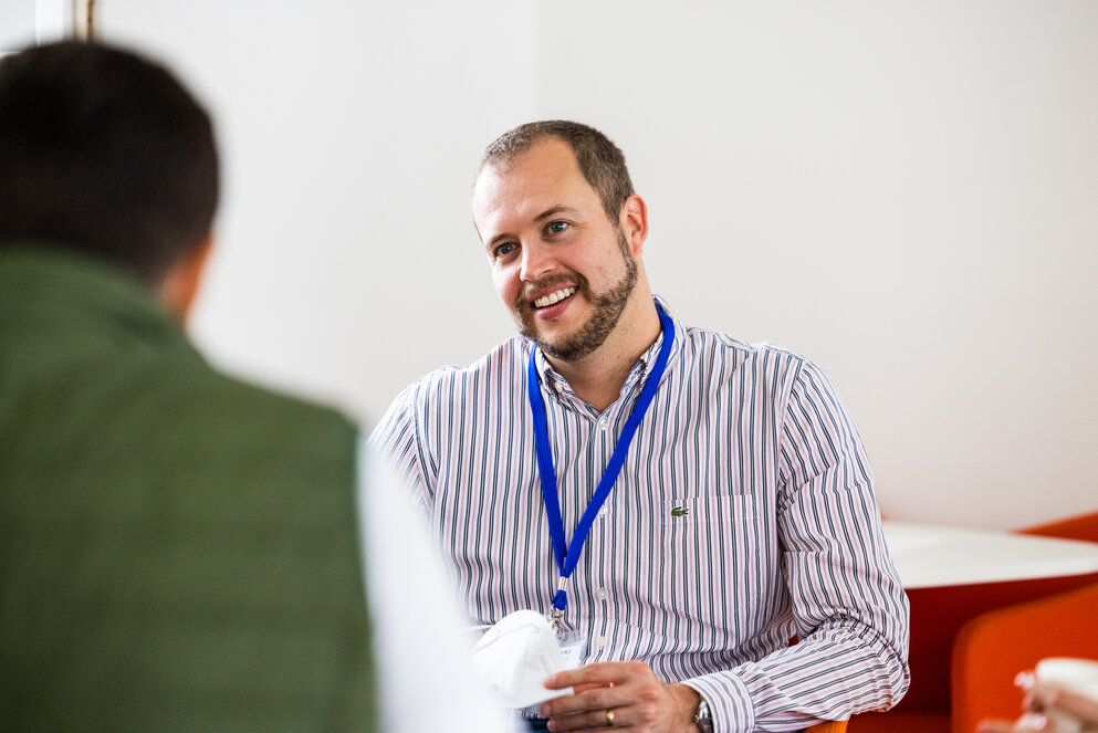Kellogg WHU EMBA Application Center A man smiling while engaged in conversation with another man