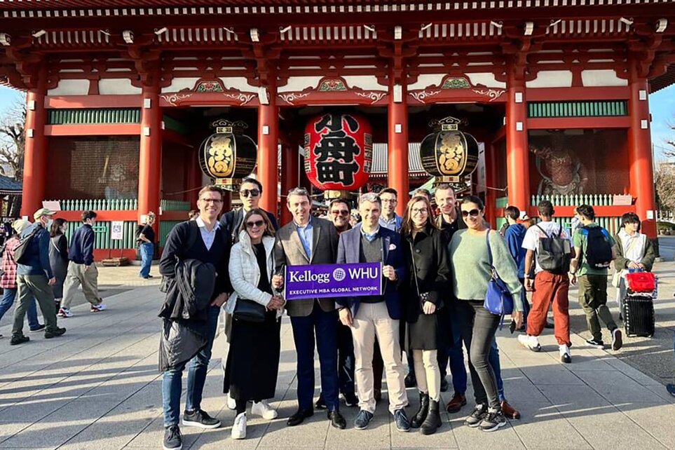 A group of people holding a banner and posing for a photo in front of a temple