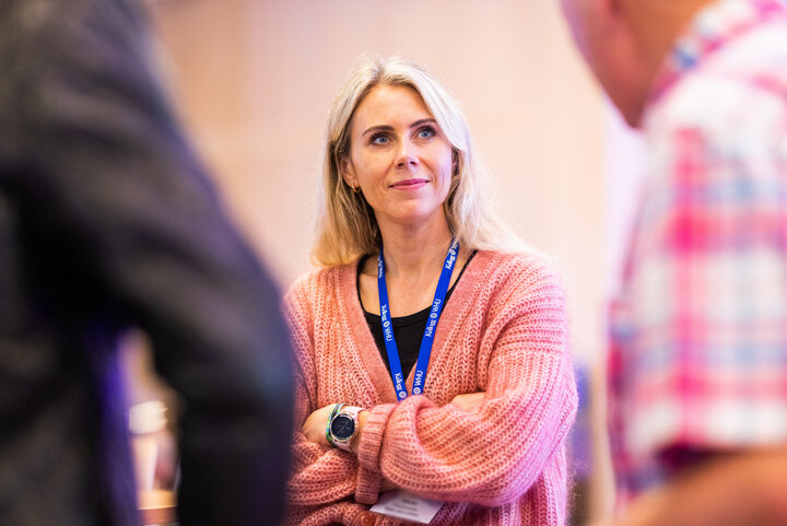 A woman in a pink sweater engaging in conversation with others