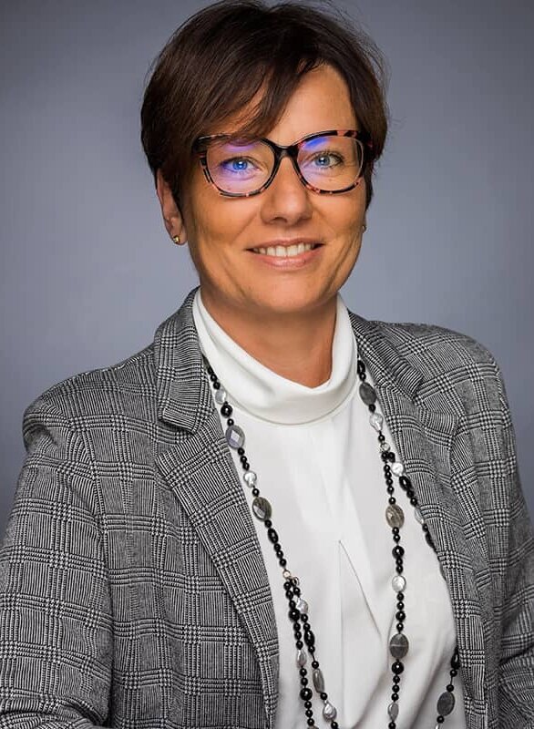 A woman in a blazer smiles at the camera