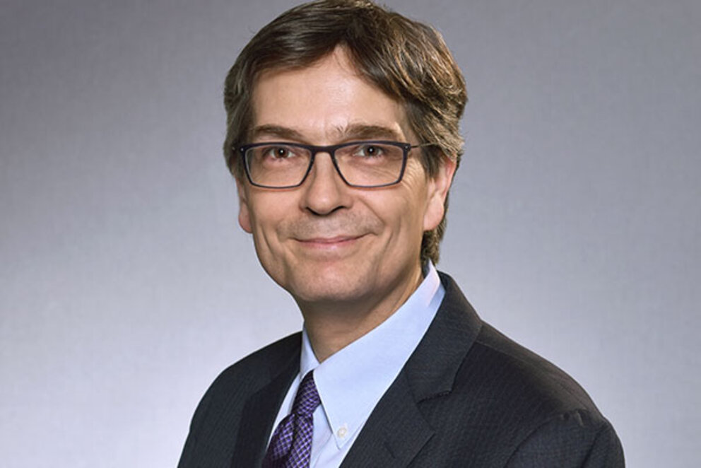 A dark blond man with glasses looks friendly into the camera