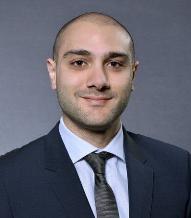 A young man in a suit looks friendly into the camera